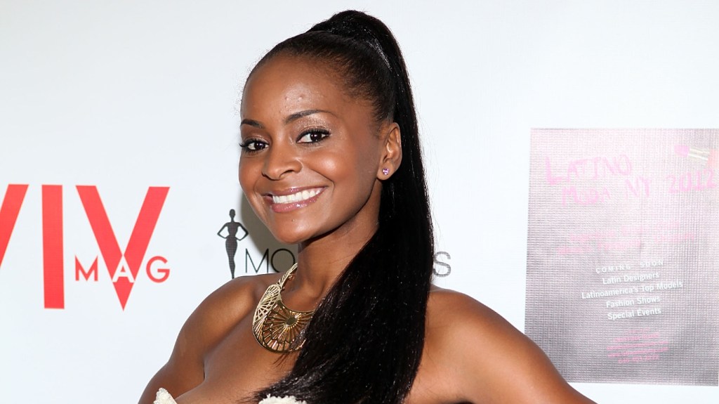 Royce Reed in a white dress and black ponytail, smiling.