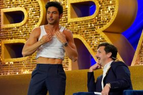 Andrea Denver on stage at BravoCon 2023 wearing a white tank-top but in the process of removing it.