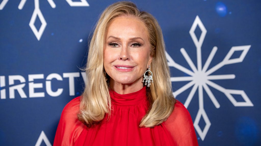 Kathy Hilton posing in a red dress, standing in front of a blue backdrop with snowflakes
