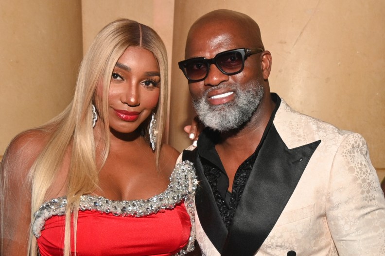 NeNe Leakes in a red dress posing with Nyonisela Sioh, who's wearing a beige suit.