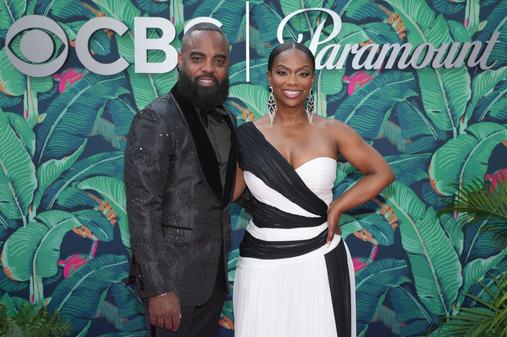 Kandi Burruss in a black and white dress posing with Todd Tucker, who is wearing a dark grey suit