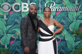 Kandi Burruss in a black and white dress posing with Todd Tucker, who is wearing a dark grey suit