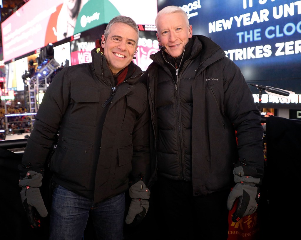 Andy Cohen and Anderson Cooper, wearing black winter coats in Times Square for New Year's Eve