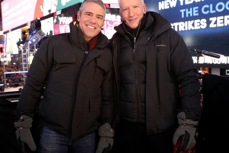 Andy Cohen and Anderson Cooper, wearing black winter coats in Times Square for New Year's Eve