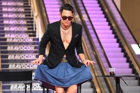 Tom Sandoval curtseying in front of a set of escalators at BravoCon 2023; he's wearing a black blazer and a denim skirt.