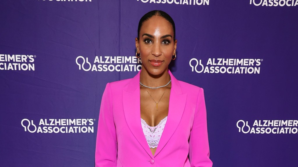 Annemarie Wiley standing in front of a purple backdrop and wearing a hot pink blazer