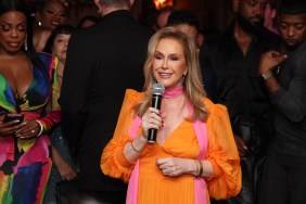 Kathy Hilton in an orange and pink dress, holding a microphone and speaking in front of a crowd