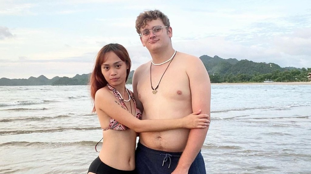 Brandan and Mary Denucciõ on a beach, Brandan is shirtless and Mary is in a bathing suit with her arms around him