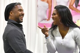 Marc daly on the left in a grey shirt smiling; Kenya Moore is on the right side smiling and pointing at him while wearing a white sweater