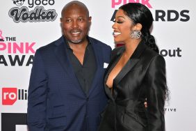 Simon and Porsha Williams Guobadia posing together at a red carpet event; Simon is wearing a blue suit while Porsha is wearing a black suit and looking at Simon from the side