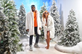 Jason Cameron and Gizelle Bryant posing in a Winter House activation at BravoCon 2023; they're both smiling and wearing white robes