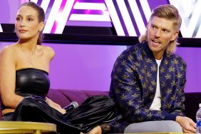 Kyle Cooke and Amanda Batula on stage at BravoCon 2023; Amanda is sitting with her legs crossed on a couch and Kyle is leaning over