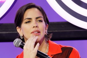 Katie Maloney in a red top, biting her lip and holding a microphone