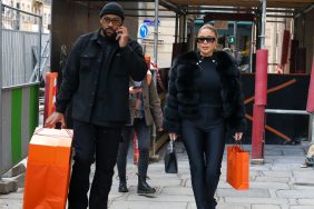 Marcus Jordan and Larsa Pippen dressed in all black and walking outside while carrying orange shopping bags