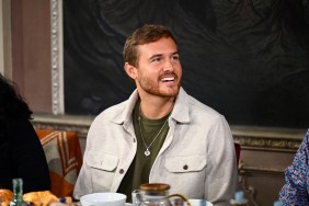 Peter Weber sitting at a table on Season 2 of The Traitors, he's smiling and wearing a green shirt under a white jacket