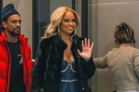 Gizelle Bryant walking outside and waving, she's wearing a black coat and walking alongside Jason Cameron, who's wearing a red jacket