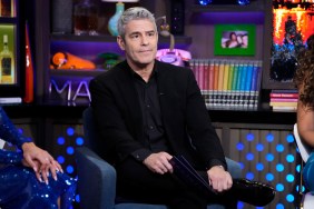 Andy Cohen sitting in a black suit and making a tense face on Watch What Happens Live
