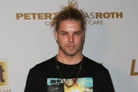 Jeremy Madix posing in front of a white backdrop wearing a messy bun and a black t-shirt