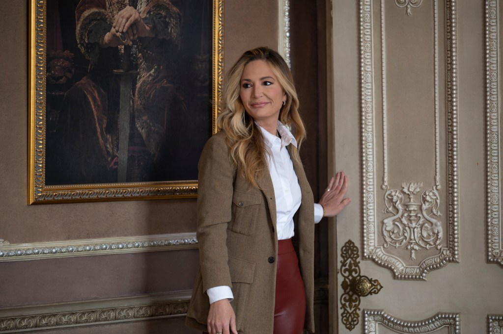 Kate Chastain walking into the breakfast room in Traitors Season 1; she's wearing red pants and a brown coat