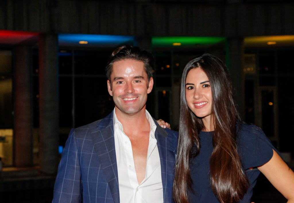 Jesse Lally in a navy blue suit and a white, unbuttoned shirt posing with Michelle Lally who is also wearing navy blue