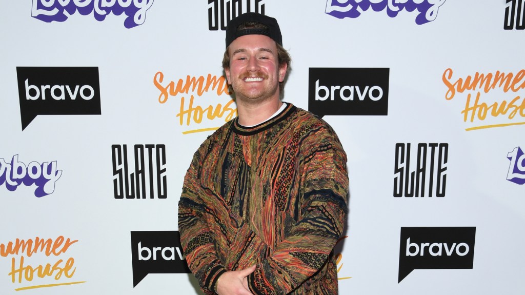 West Wilson at the Summer House Season 8 premiere posing in a brown sweater