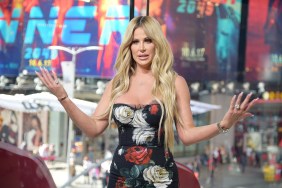 Kim Zolciak on Extra, wearing a floral dress and holding her hands up, shrugging her shoulders