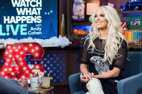 Erika Jayne in a black outfit, smiling and sitting in a a chair on Watch What Happens Live