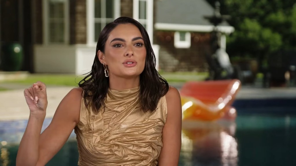 Paige DeSorbo in a gold dress during a Summer House Season 8 confessional interview; she's pointing her finger in an passionate gesture