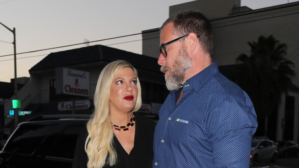 Tori Spelling in a black dress looking up at Dean McDermott, who is looking away from the camera and wearing a blue shirt
