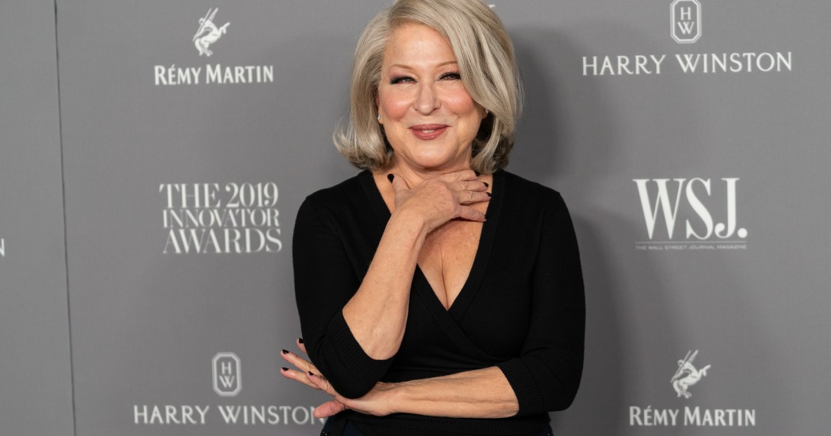 Bette Midler posing in a black dress with her hand around her neck