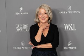 Bette Midler posing in a black dress with her hand around her neck