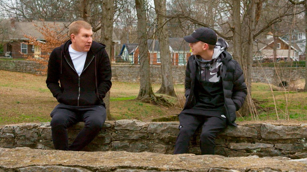 Todd Chrisley and Grayson Chrisley wearing black hoodies and sitting across from each other on Chrisley Knows Best