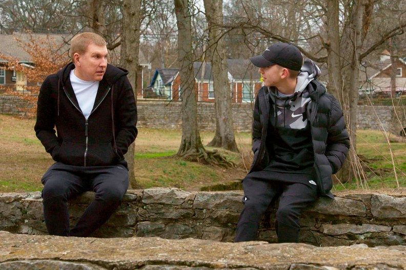 Todd Chrisley and Grayson Chrisley wearing black hoodies and sitting across from each other on Chrisley Knows Best