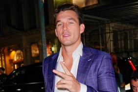 Tyler Cameron throwing up the "peace" sign and wearing an unbuttoned purple suit with his chest exposed