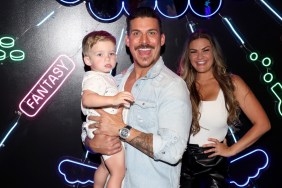 Jax Taylor and Brittany Cartwright posing together with their son, Cruz. Jax is holding Cruz and smiling