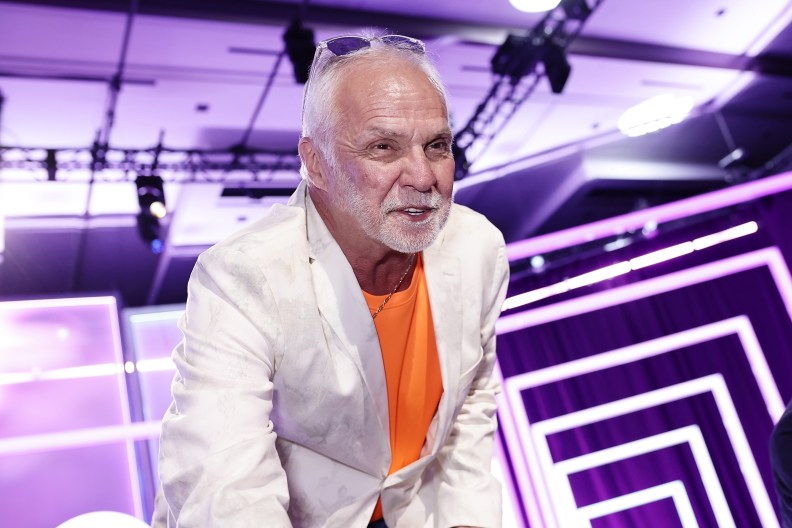 Captain Lee Rosbach at BravoCon wearing an orange shirt and a white blazer; he's leaning over towards the camera and squinting