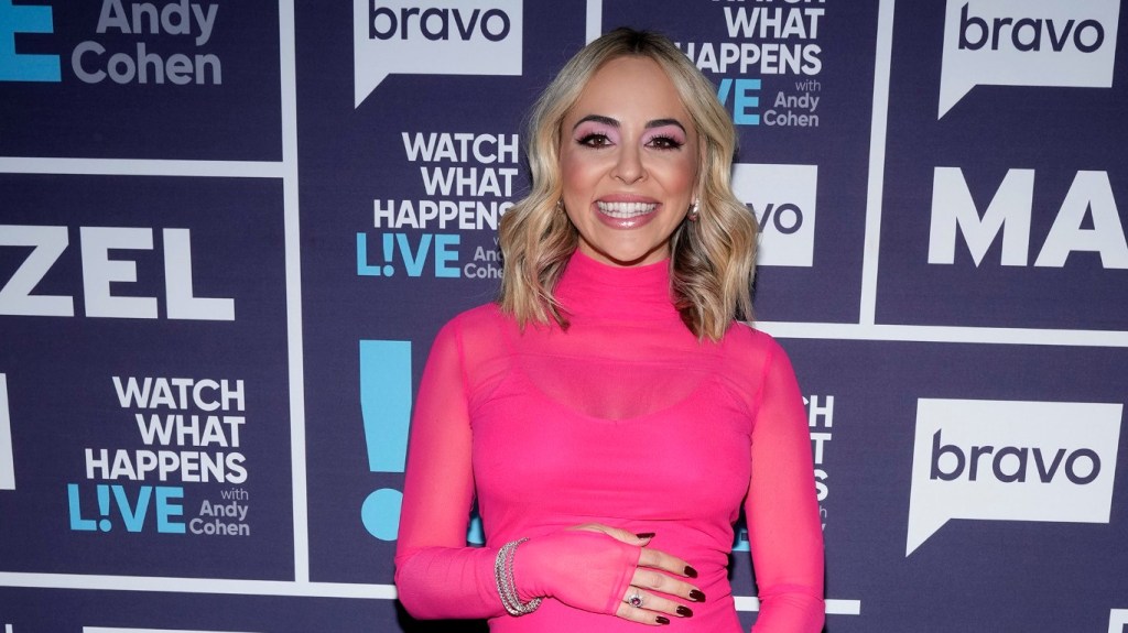 Dr. Nicole Martin backstage at Watch What Happens Live; she's smiling, wearing a pink dress, and resting her hand on her baby bump