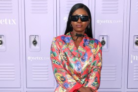 Faith Stowers posing in front of purple lockers, she's wearing a multicolored blazer and has sunglasses on.