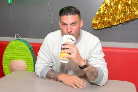 Jax Taylor sitting at a restaurant, wearing a grey sweater, and drinking out of a large soda cup