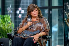Abby Lee Miller making a stern face and holding a microphone