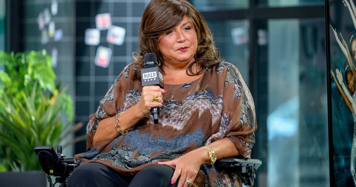 Abby Lee Miller making a stern face and holding a microphone