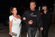 Kyle Richards in a white dress walking arm in arm with Mauricio Umansky who is wearing jeans and a black t-shirt