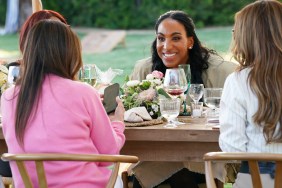 Annemarie Wiley sitting at a table and grinning during a scene on Real Housewives of Beverly Hills
