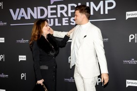 On the left, Lisa Vanderpump in a black suit facing Tom Schwartz, who is on the right in a white suit; their hands are on each other's shoulders