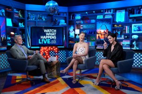 Andy Cohen, Ariana Madix, and Katie Maloney smiling and sitting on the set of Watch What Happens Live; Katie is pointing her finger in the air