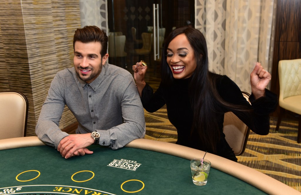 Rachel Lindsay at Bryan Abasolo sitting at a casino table and smiling