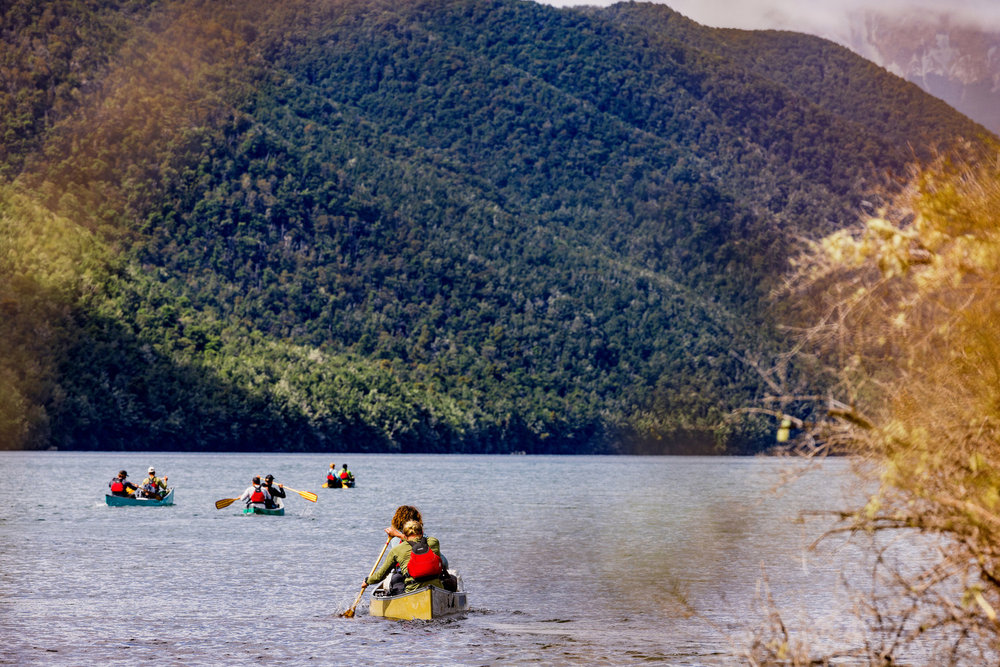 Boats paddling across a lake on Race to Survive: New Zealand