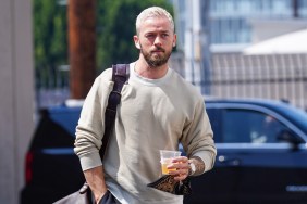 Artem Chigvinstev walking in a grey sweater and holding a beverage