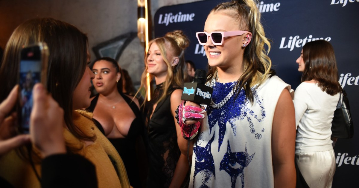 JoJo Siwa speaking into a microphone during a red carpet interview