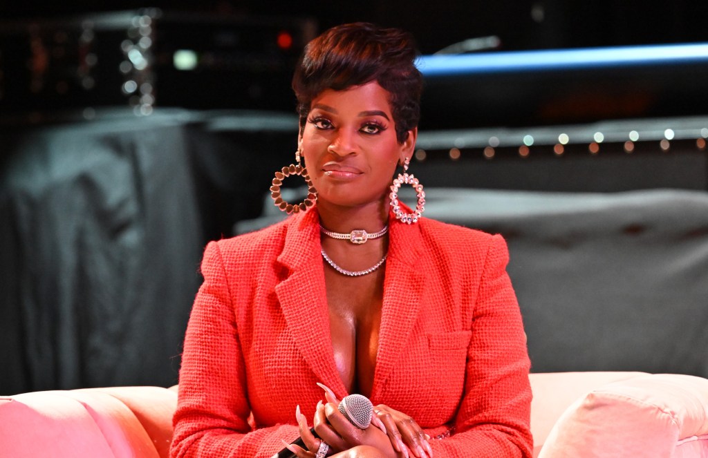 Shamea Morton in a red blazer holding a microphone